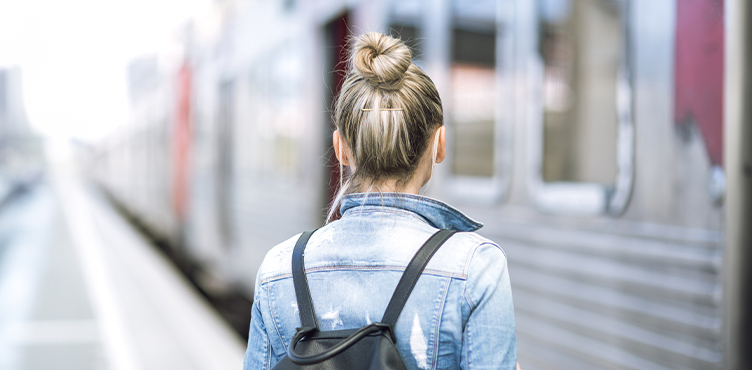Ung kvinna på tågperrong sedd bakirån.