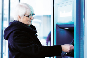 Äldre kvinna vid bankomat.