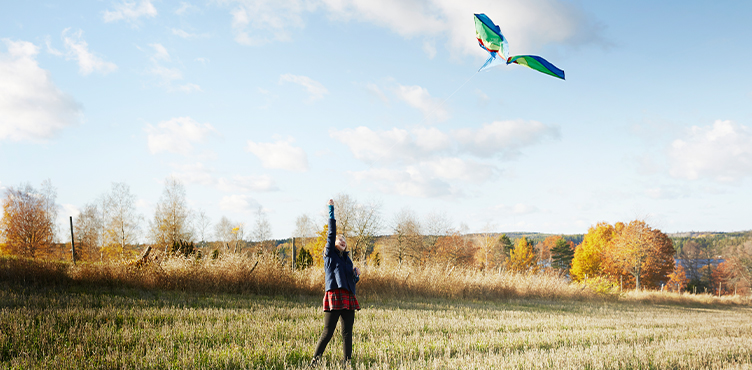 Girl flying kite on meadow.
