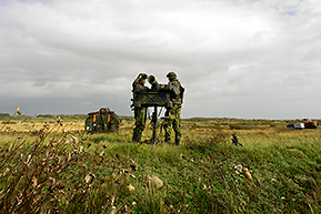 Militärer med artilleripjäs på ett fält.